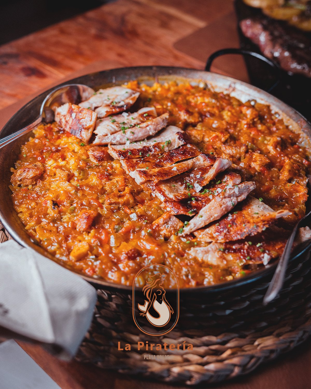 Paella de secreto ibérico de La Piratería, con el secreto laminado sobre el arroz